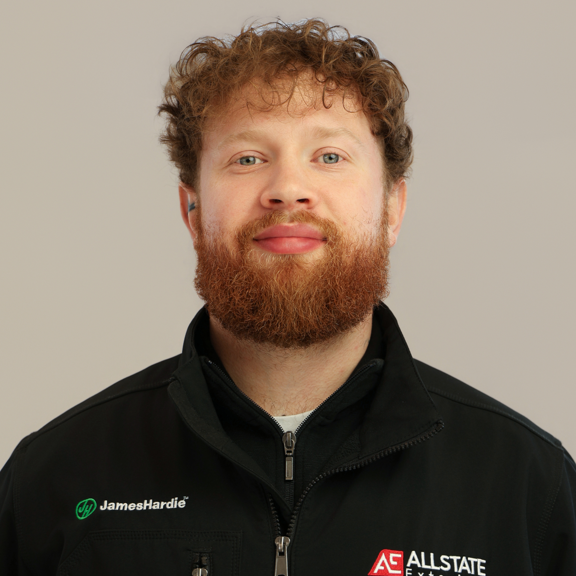 A man with a beard is wearing a blue and gray polo shirt.