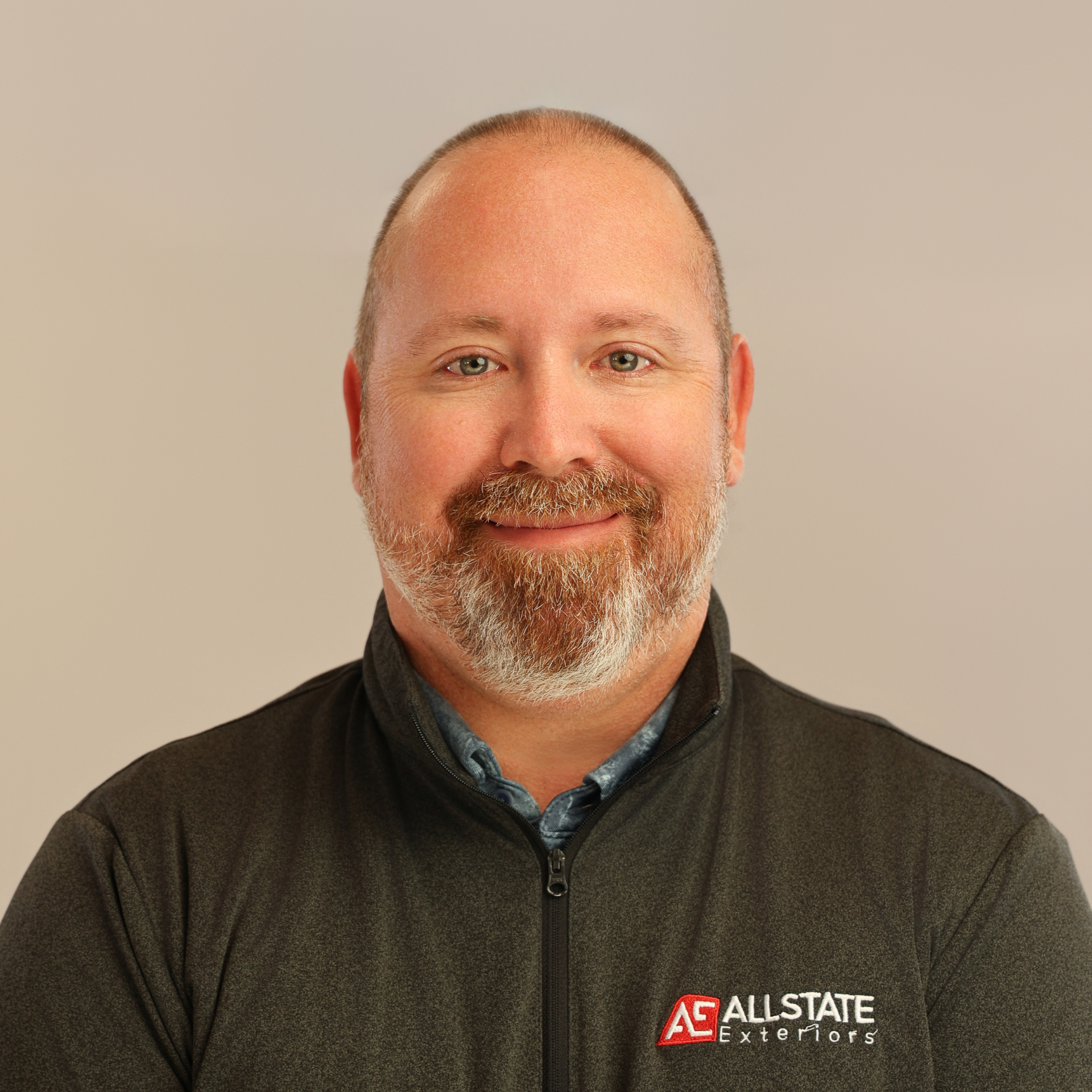 A man with a beard is smiling for the camera while wearing a black shirt.