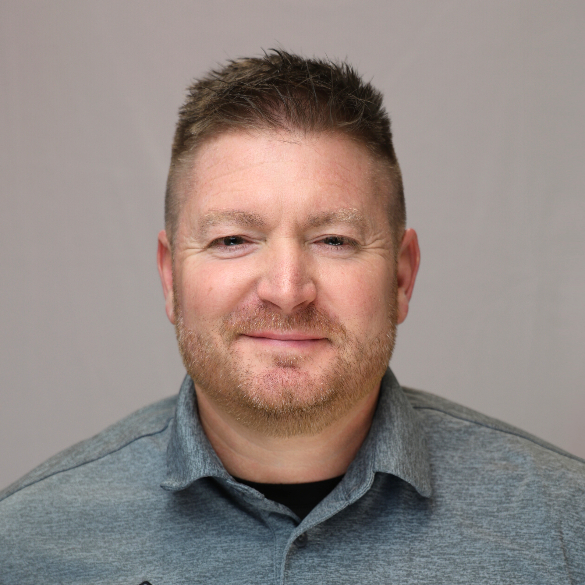 A woman with white hair is smiling for the camera while wearing a black jacket and a red shirt.
