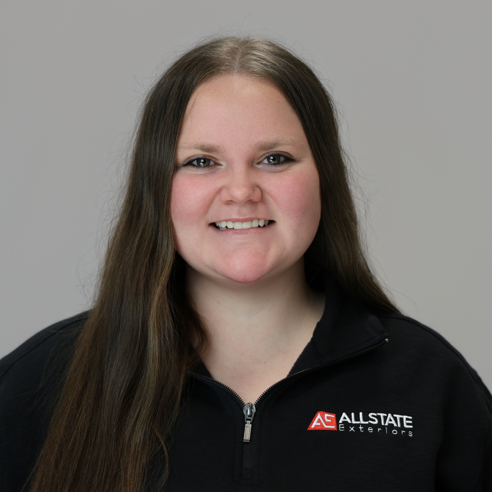A man is wearing a black jacket and smiling for the camera.