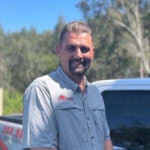 A man with a beard is standing in front of a truck.