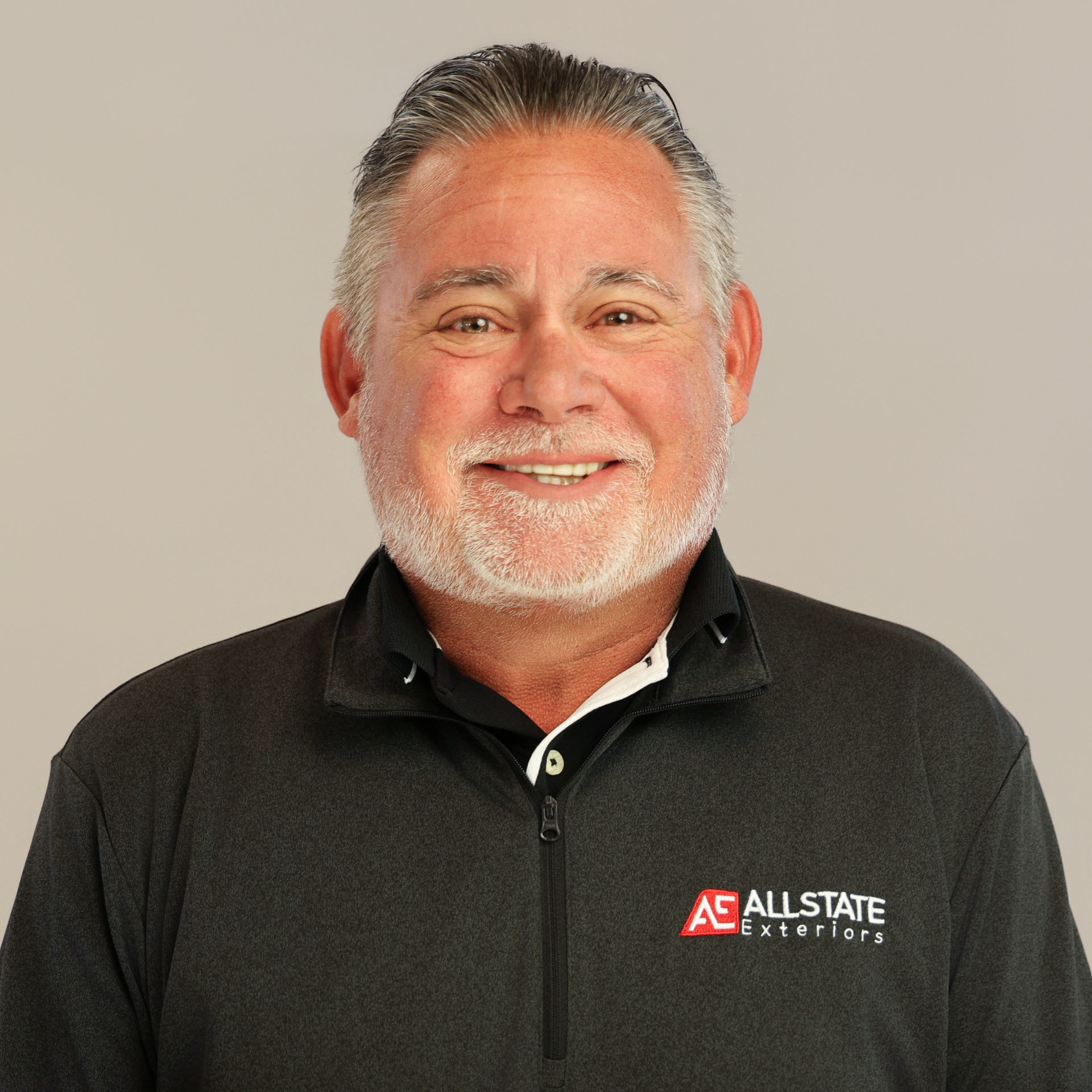 A man with a white beard smiling to the camera.