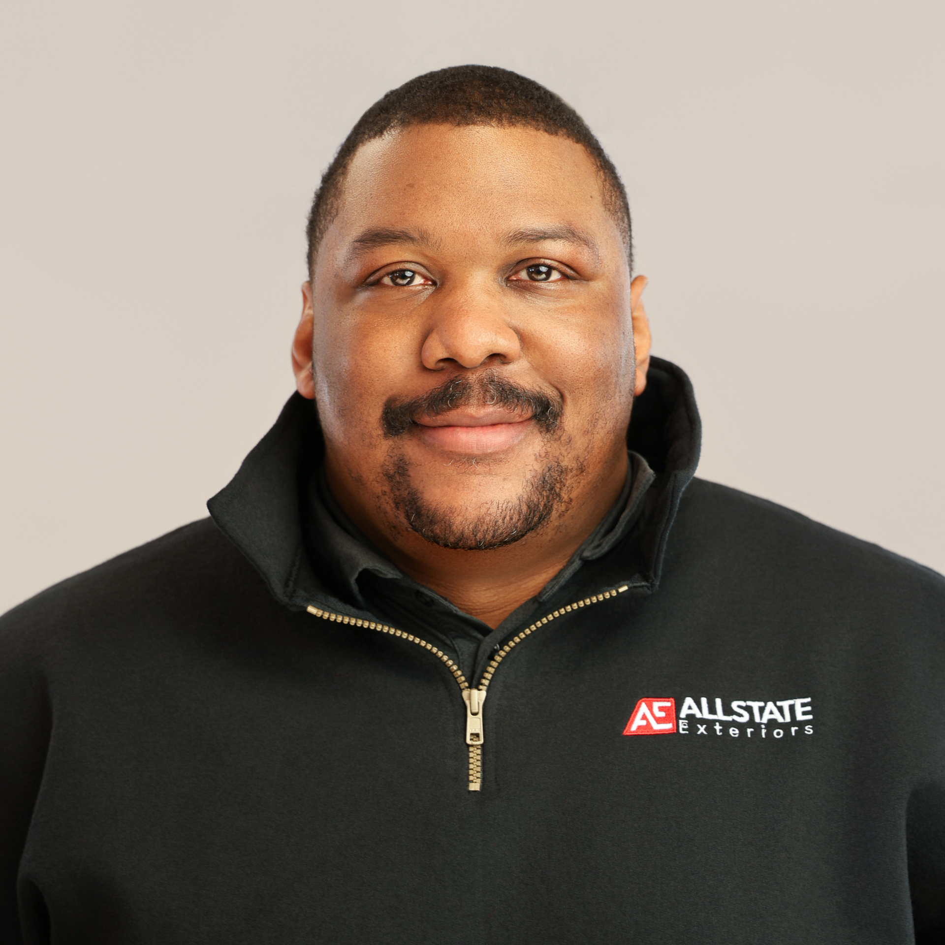A man in a grey shirt is leaning against a truck.
