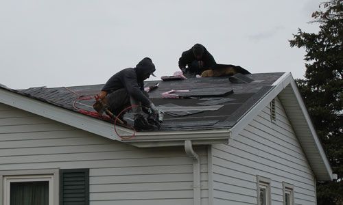 two men are working on the roof of a house
