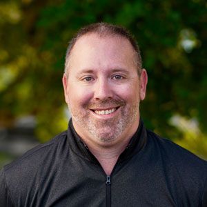 A man with a beard is smiling for the camera while wearing a black shirt.