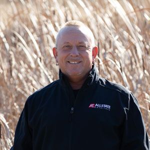 a man in a black jacket is standing in a field of tall grass