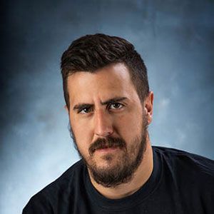 a man with a beard and mustache is wearing a black shirt and looking at the camera