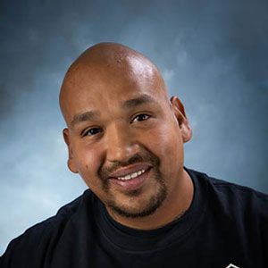 A bald man with a beard is smiling for the camera while wearing a black shirt.