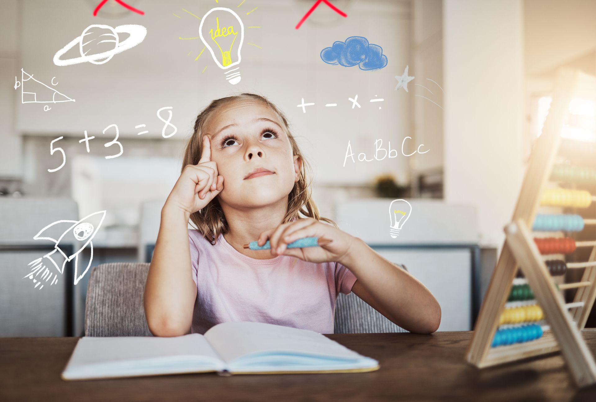 A little girl is sitting at a table with a book and an abacus.