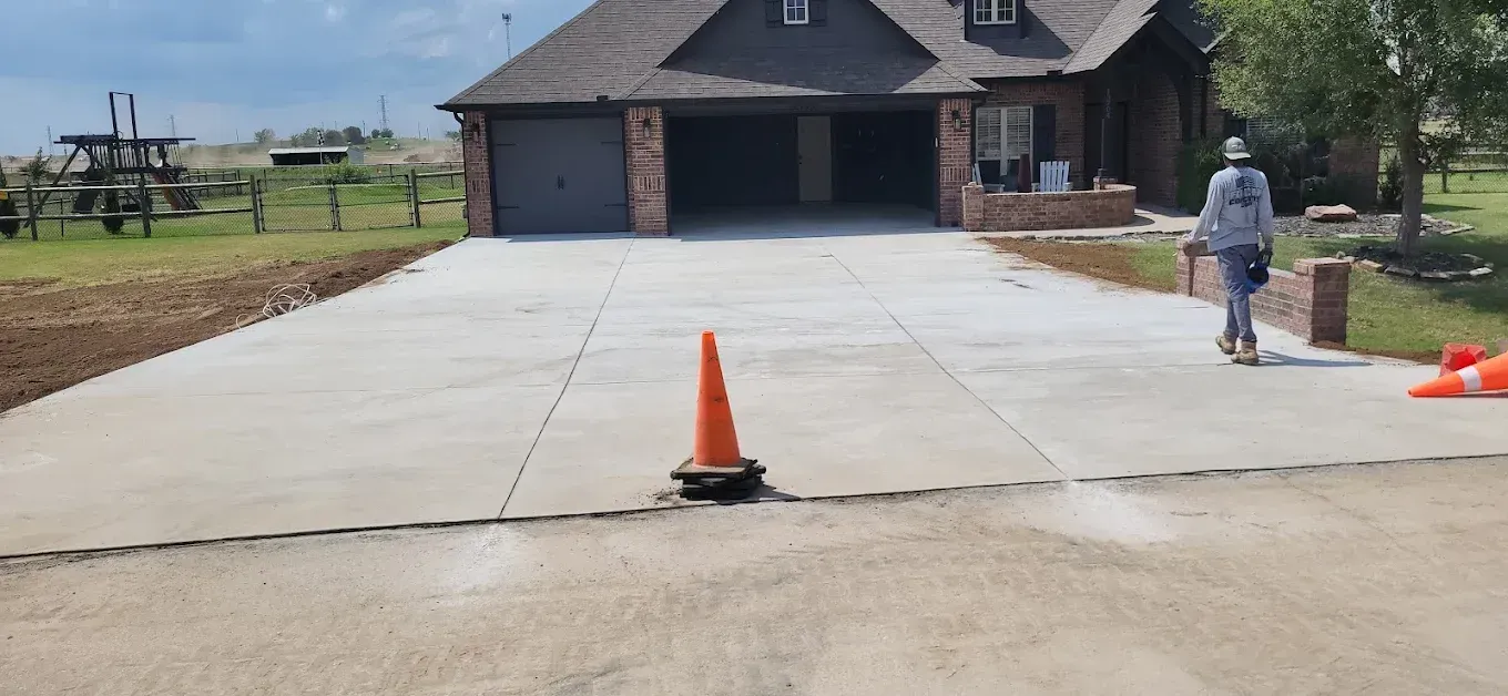 Two-story brick house with a tan garage door, green lawn, and concrete driveway on a sunny day.