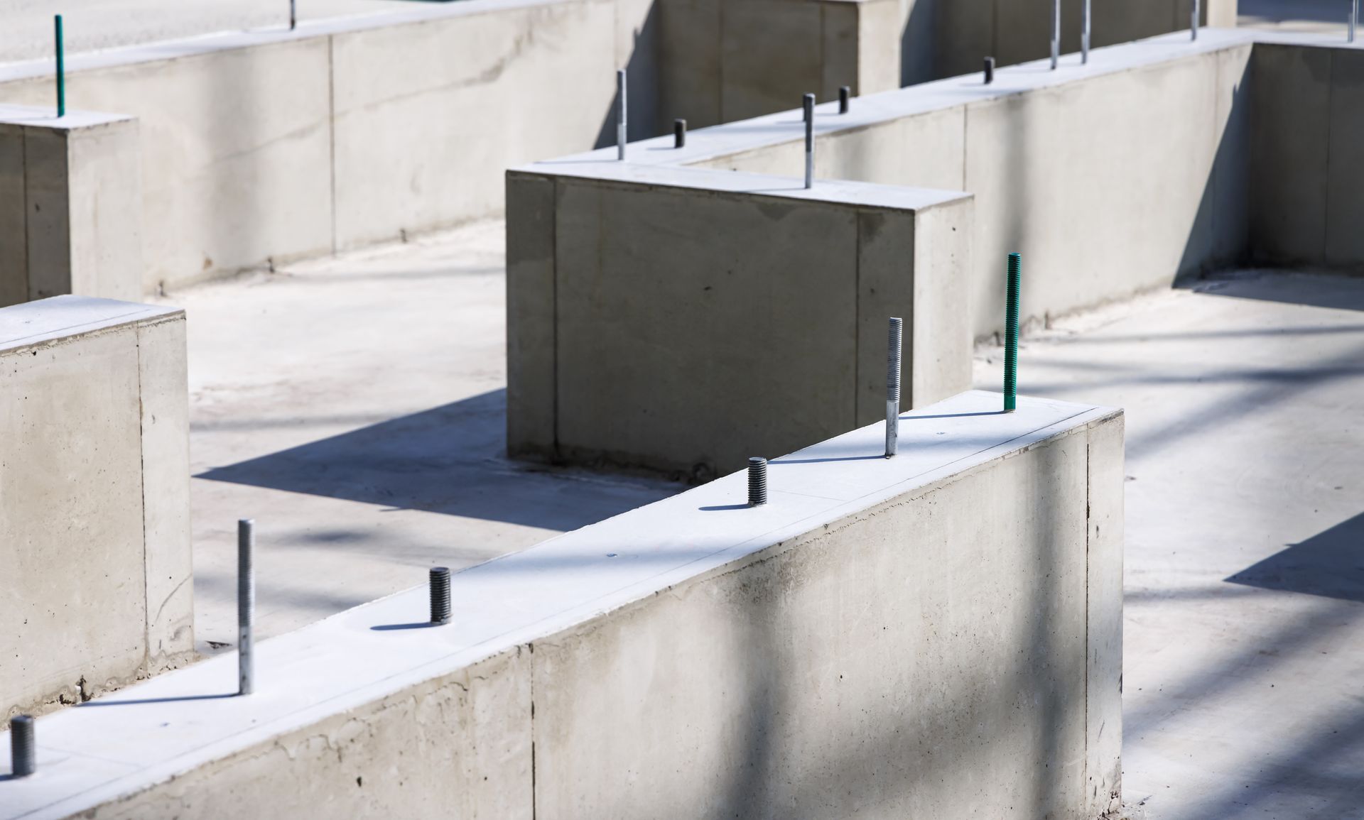 Concrete foundation of a building under construction, with protruding metal rods.