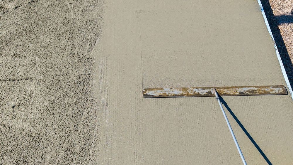 Concrete being smoothed with a trowel, creating a finished surface.