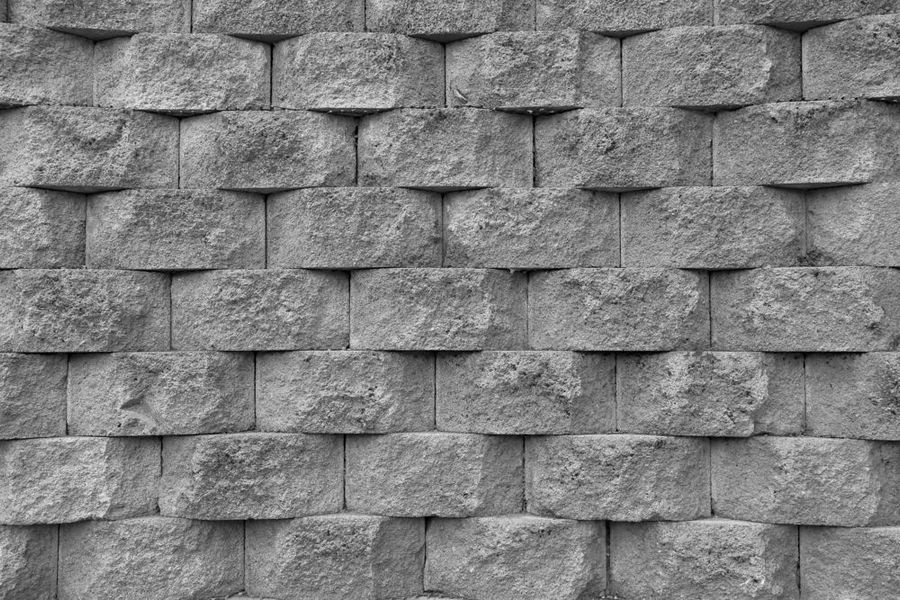 Gray, textured retaining wall made of stacked concrete blocks.