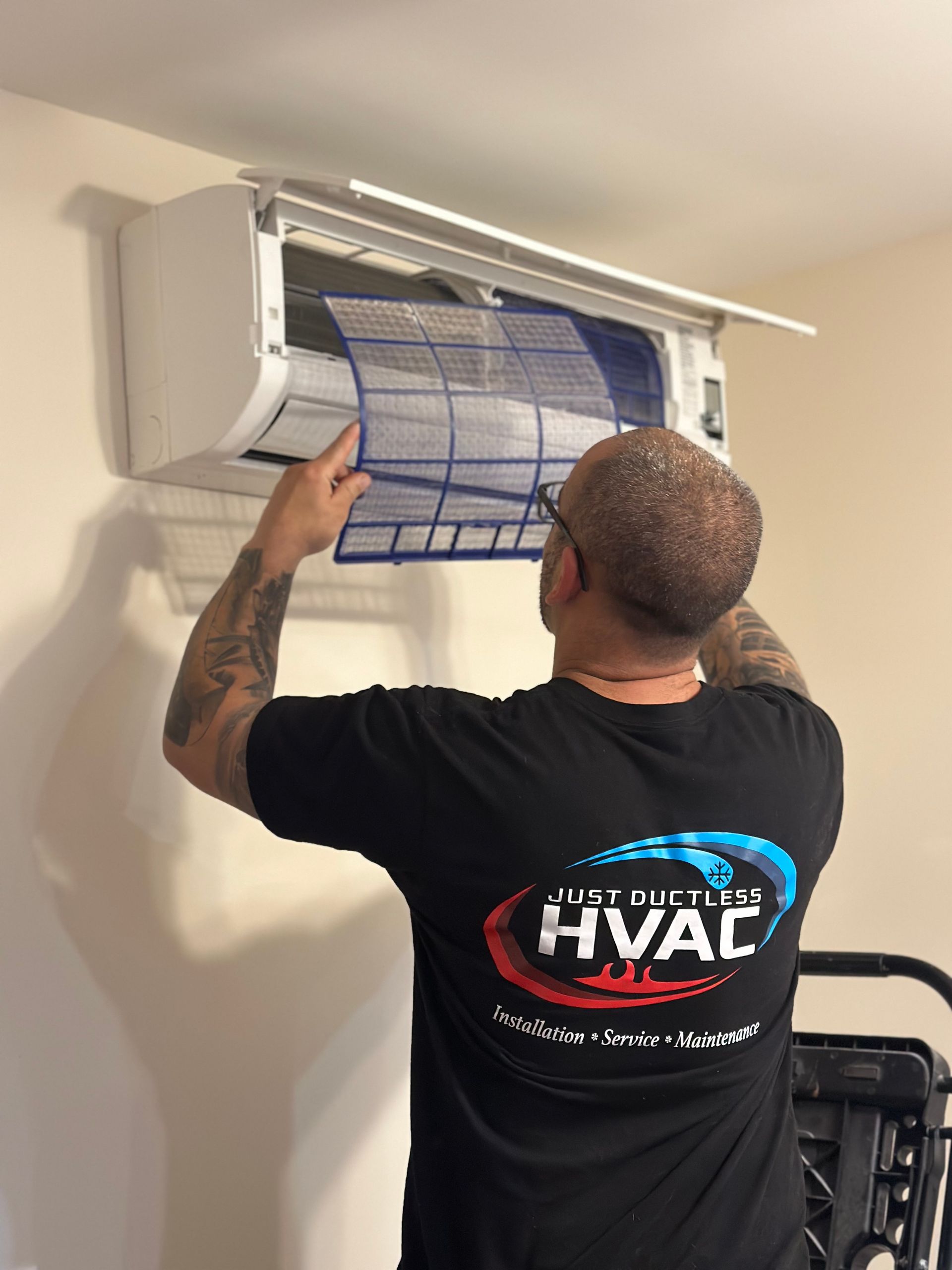 A man is working on an air conditioner on top of a building.