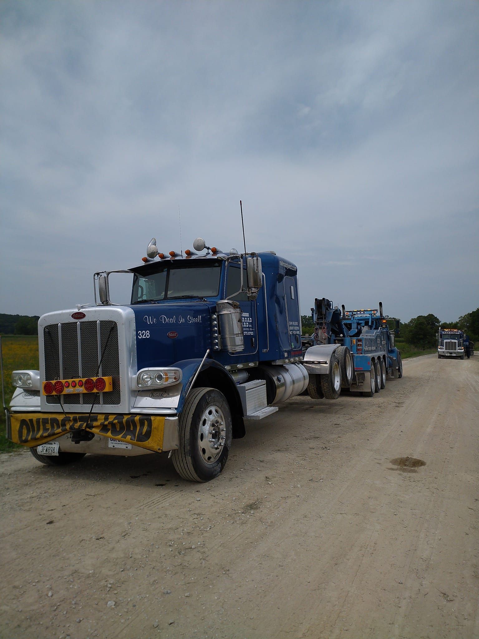 heavy duty wrecker tows a semi cab with an 'oversize load' sign