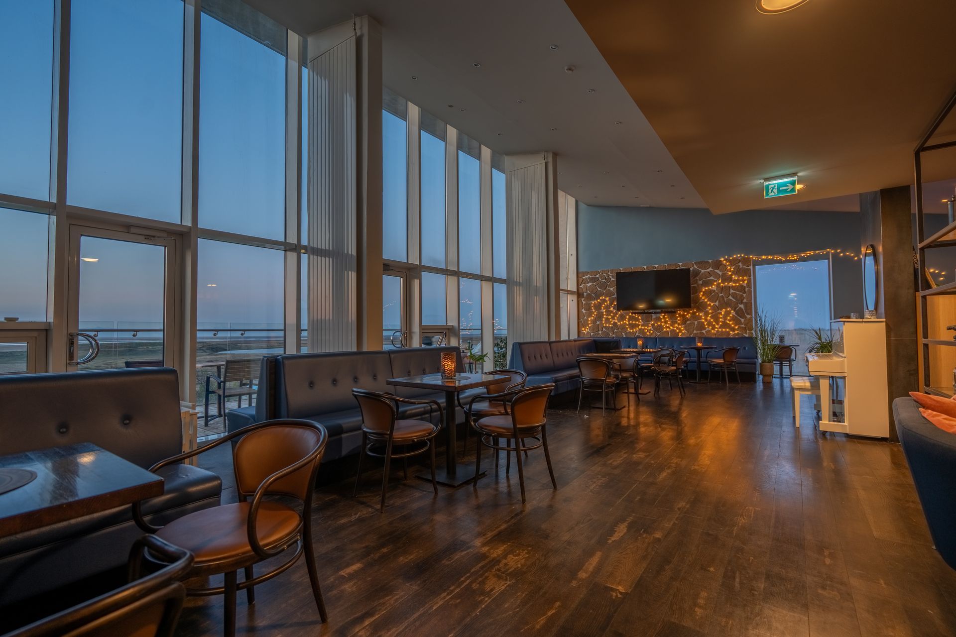 A restaurant with a lot of windows and tables and chairs.