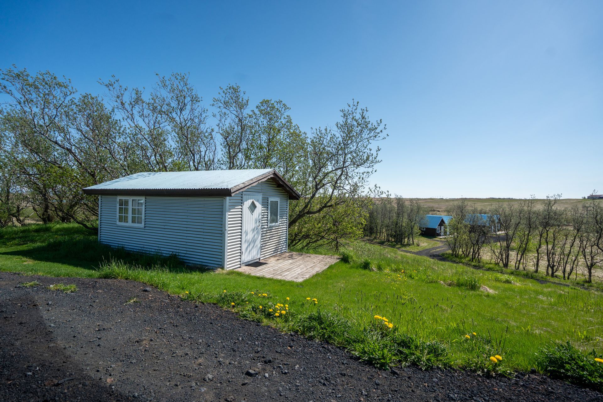 A small white house is sitting on top of a grassy hill.