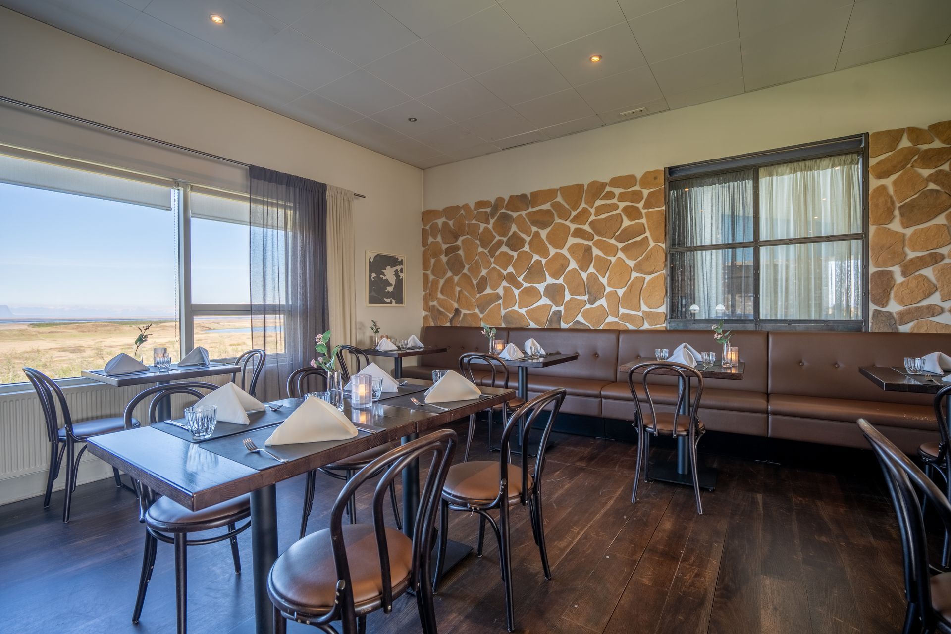 A restaurant with tables and chairs and a large window.