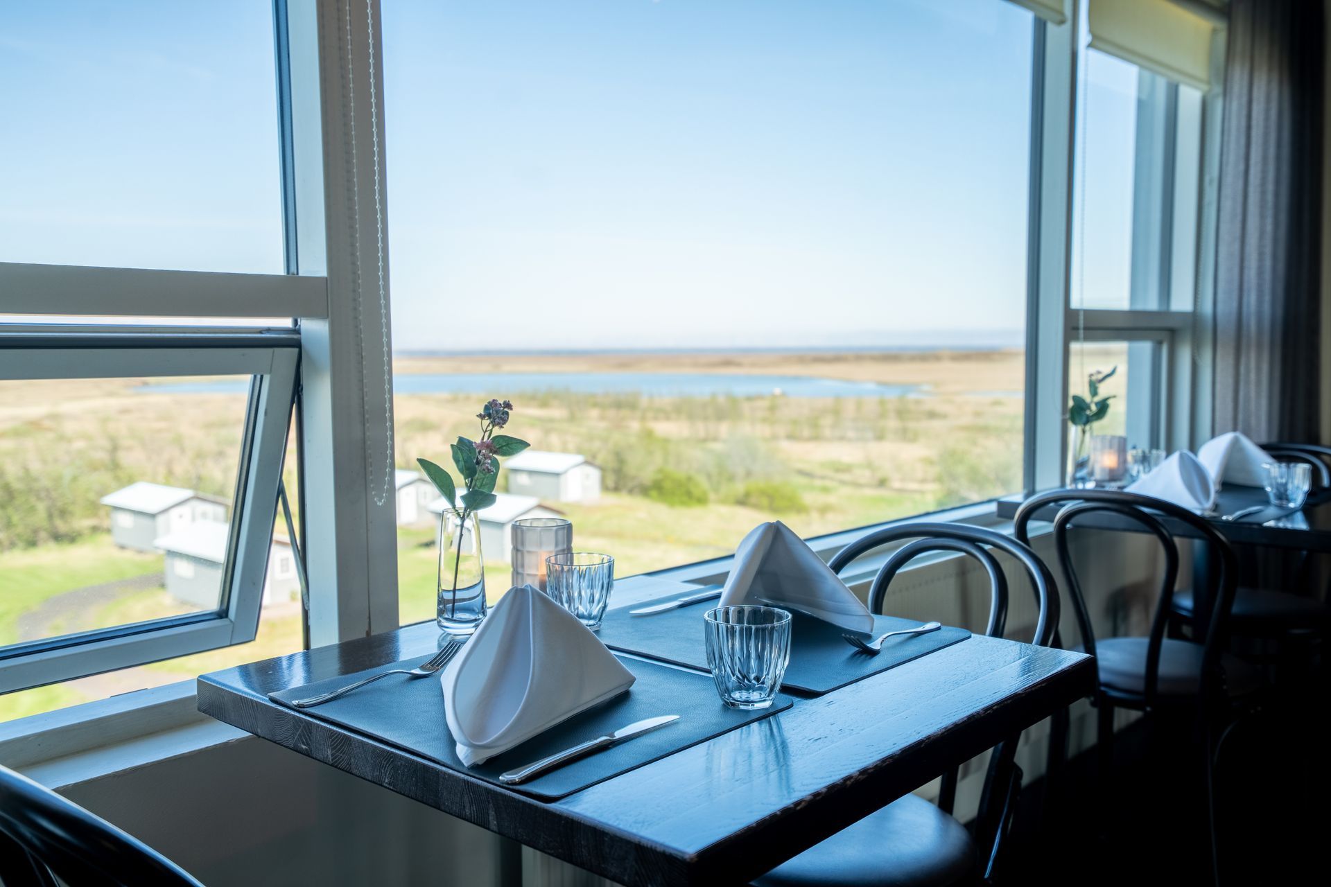 A restaurant with tables and chairs and a view of the ocean.