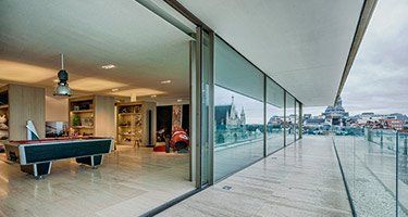 Modern interior with pool table and sliding glass doors opening to a balcony with city view.