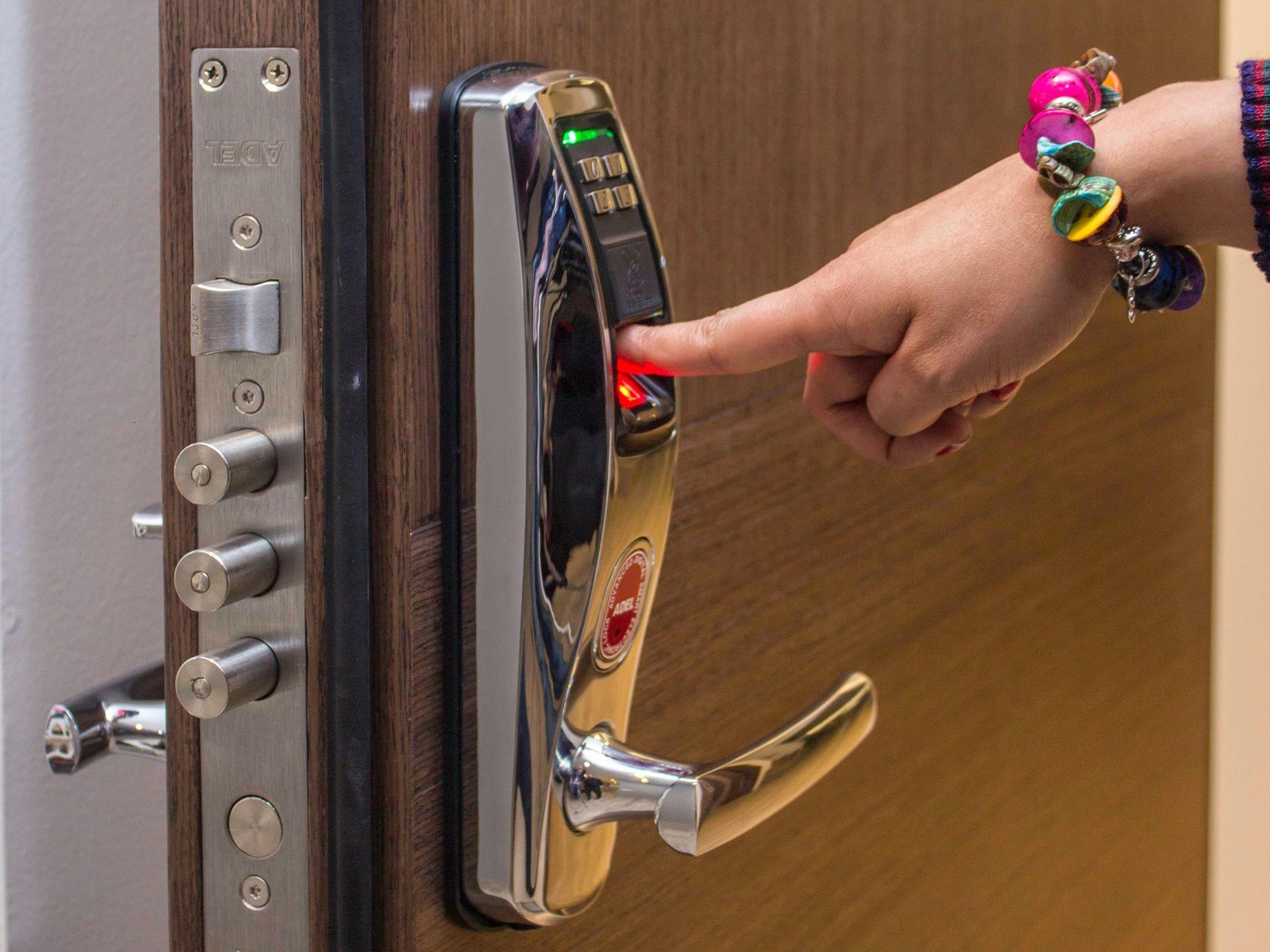 A person is pressing a button on a door lock with their finger.