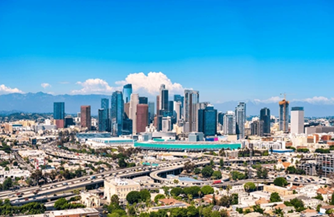 Downtown Los Angeles skyline with modern skyscrapers under a bright blue sky.
