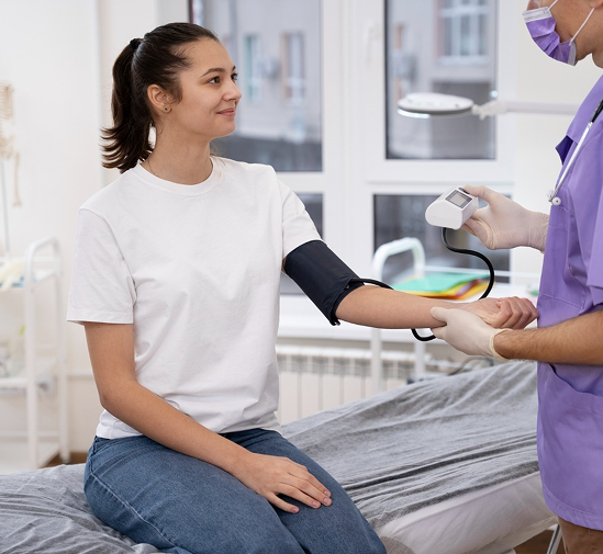 Woman has blood pressure checked by medical professional in a clinic.