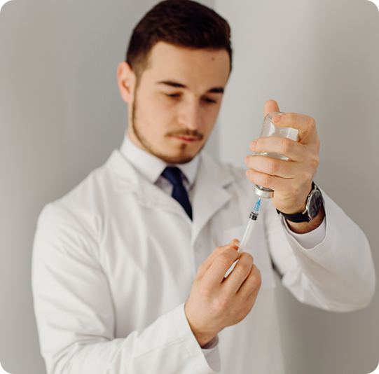 A doctor in a white coat prepares a syringe, drawing medicine from a vial.