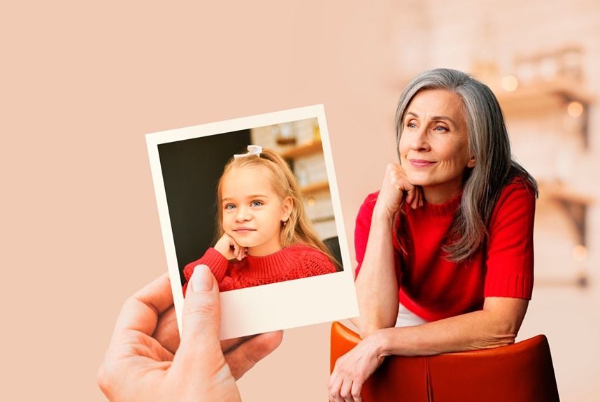 Woman looks at a photo of a young girl; both are wearing red, indoors.
