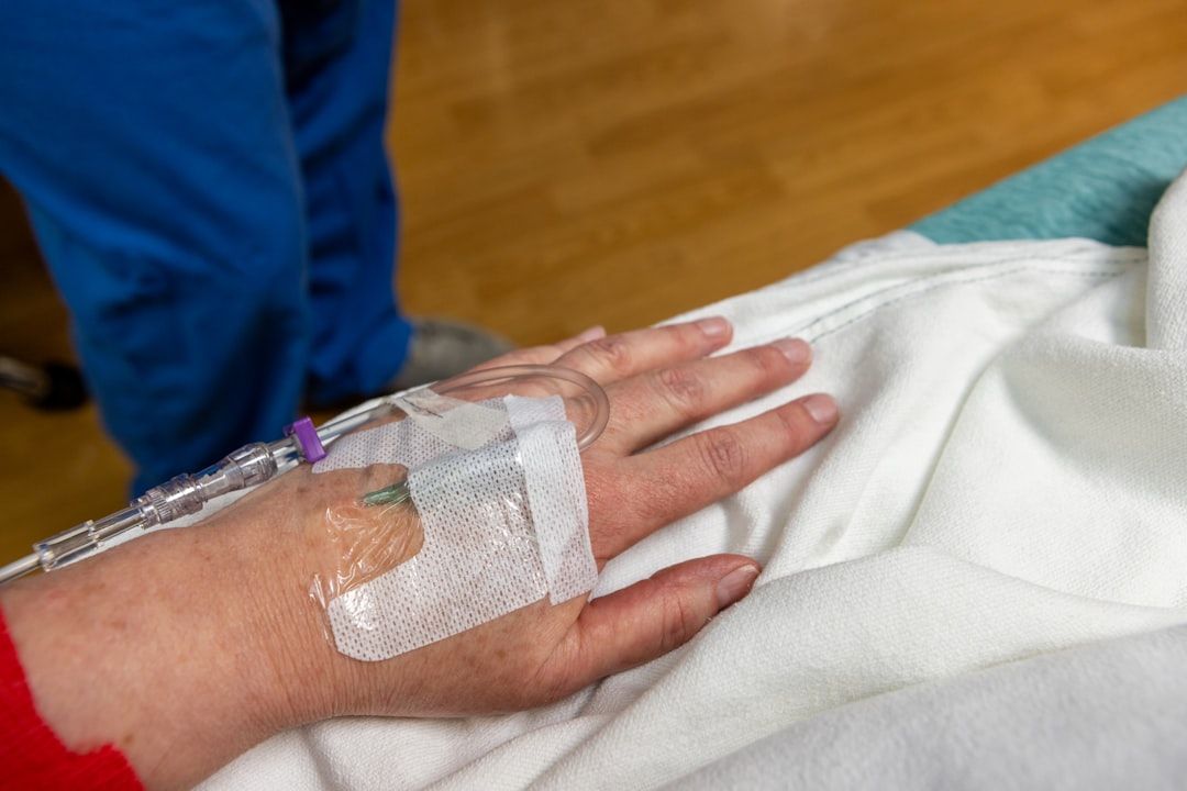 Hand with IV drip line taped, in a hospital setting.
