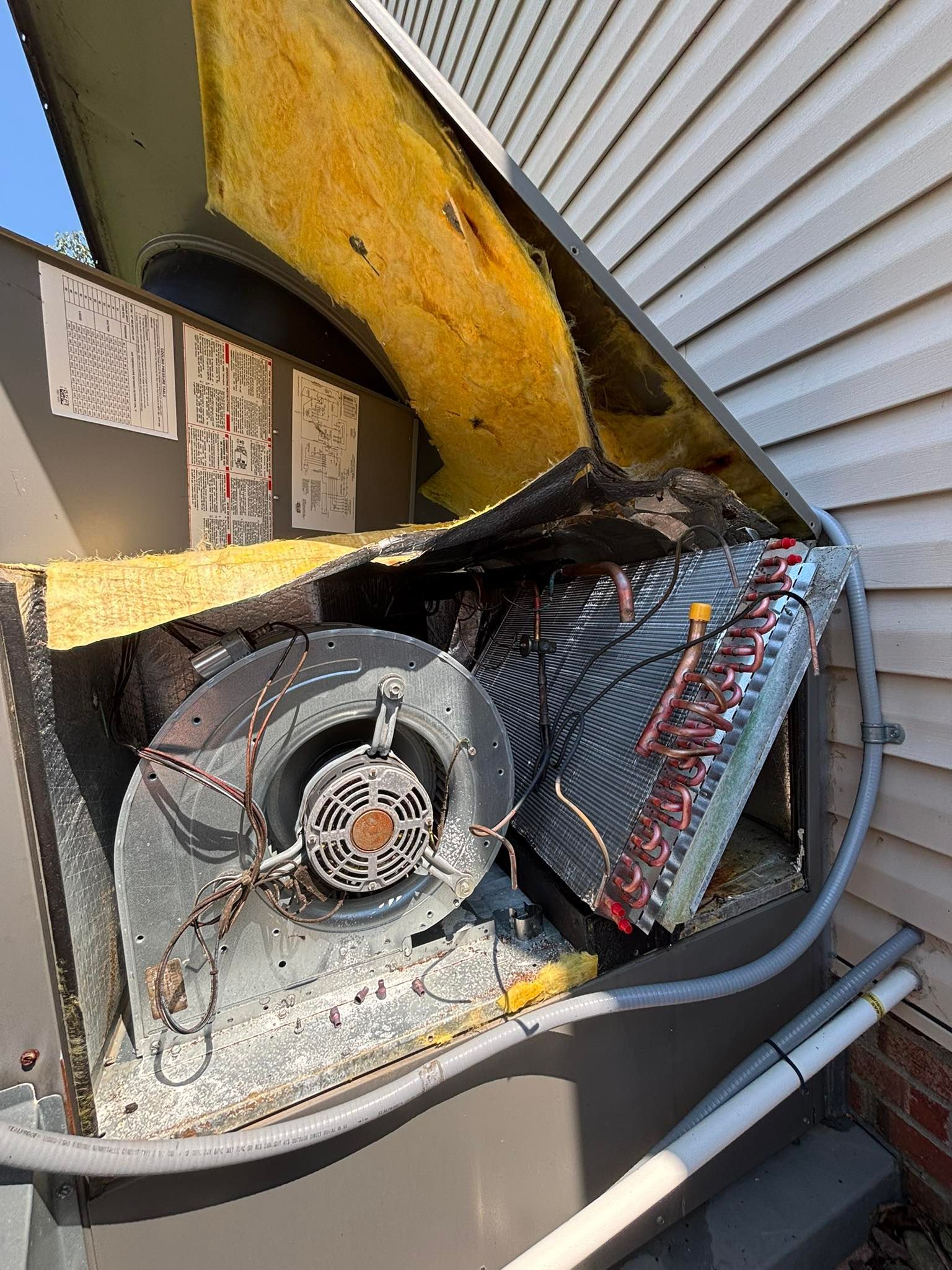 A broken air conditioner is sitting on the side of a house.
