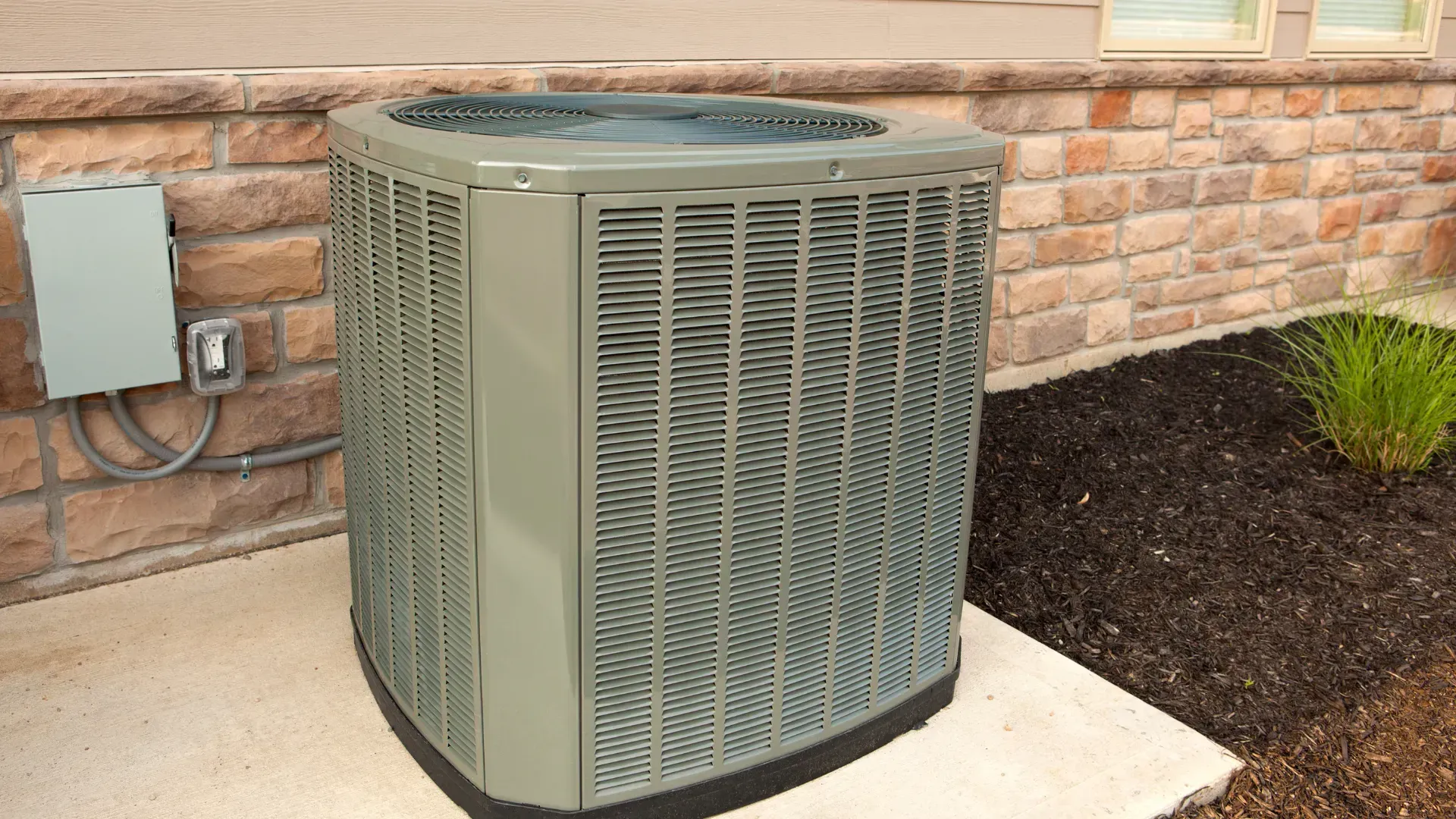 An air conditioner is sitting on the side of a brick building.