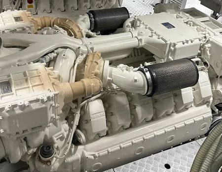A large, white marine engine with twin turbochargers and carbon-fiber air filters, installed in a clean engine room.