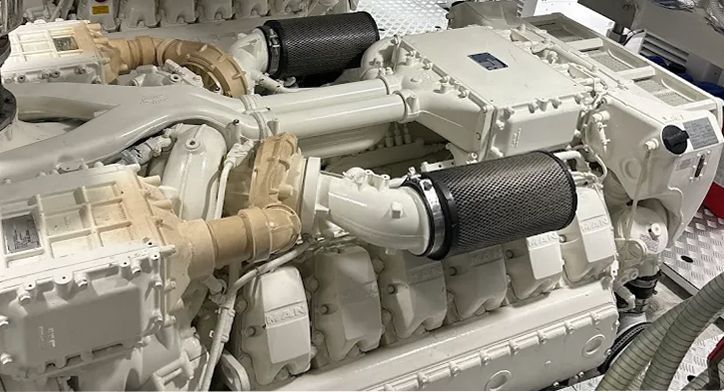 A high-angle view of a white, industrial marine diesel engine featuring large, textured dark carbon fiber air intakes.
