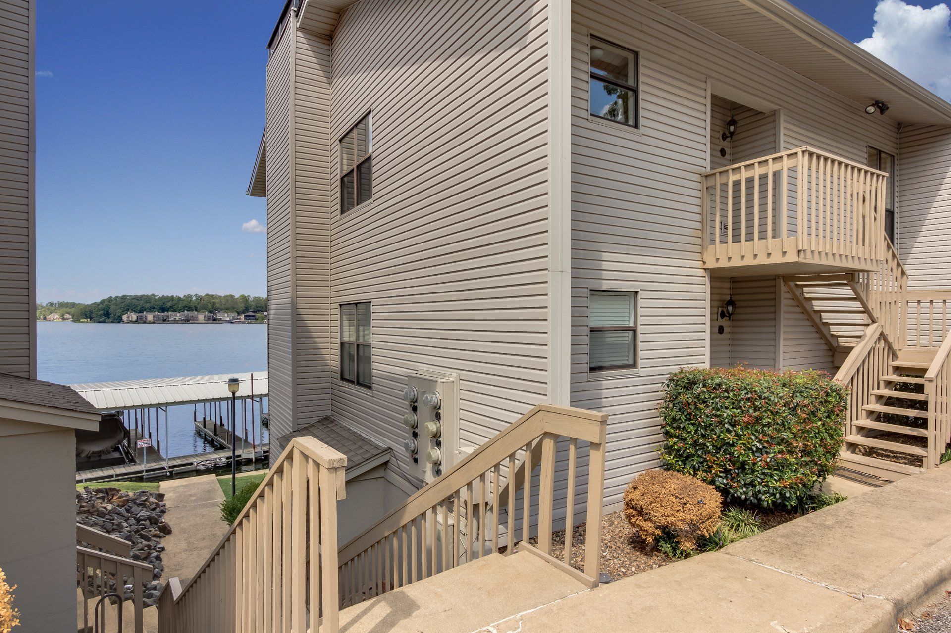 A white house with stairs leading up to it and a view of a lake