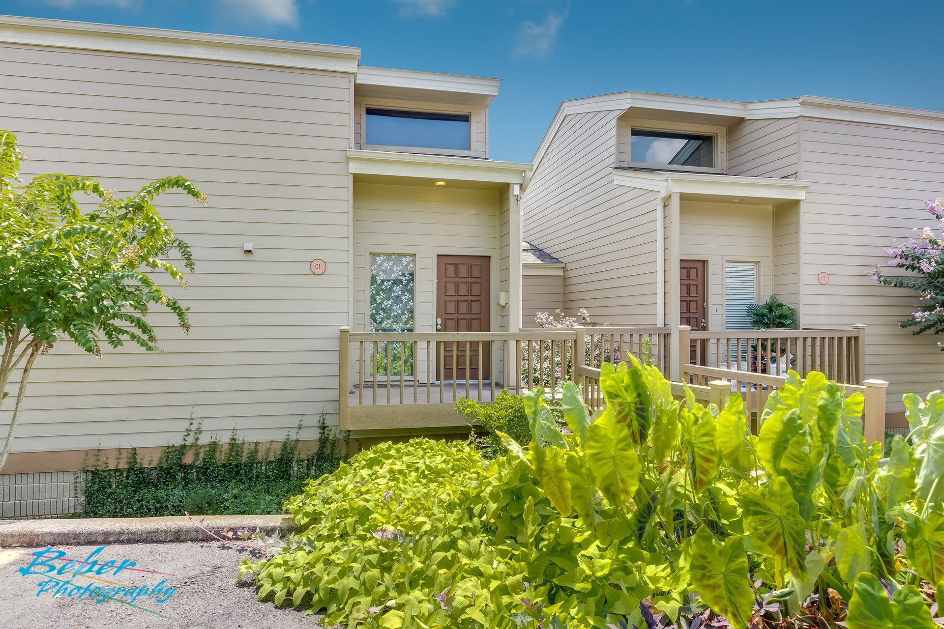 A house with a balcony and a lot of plants in front of it.