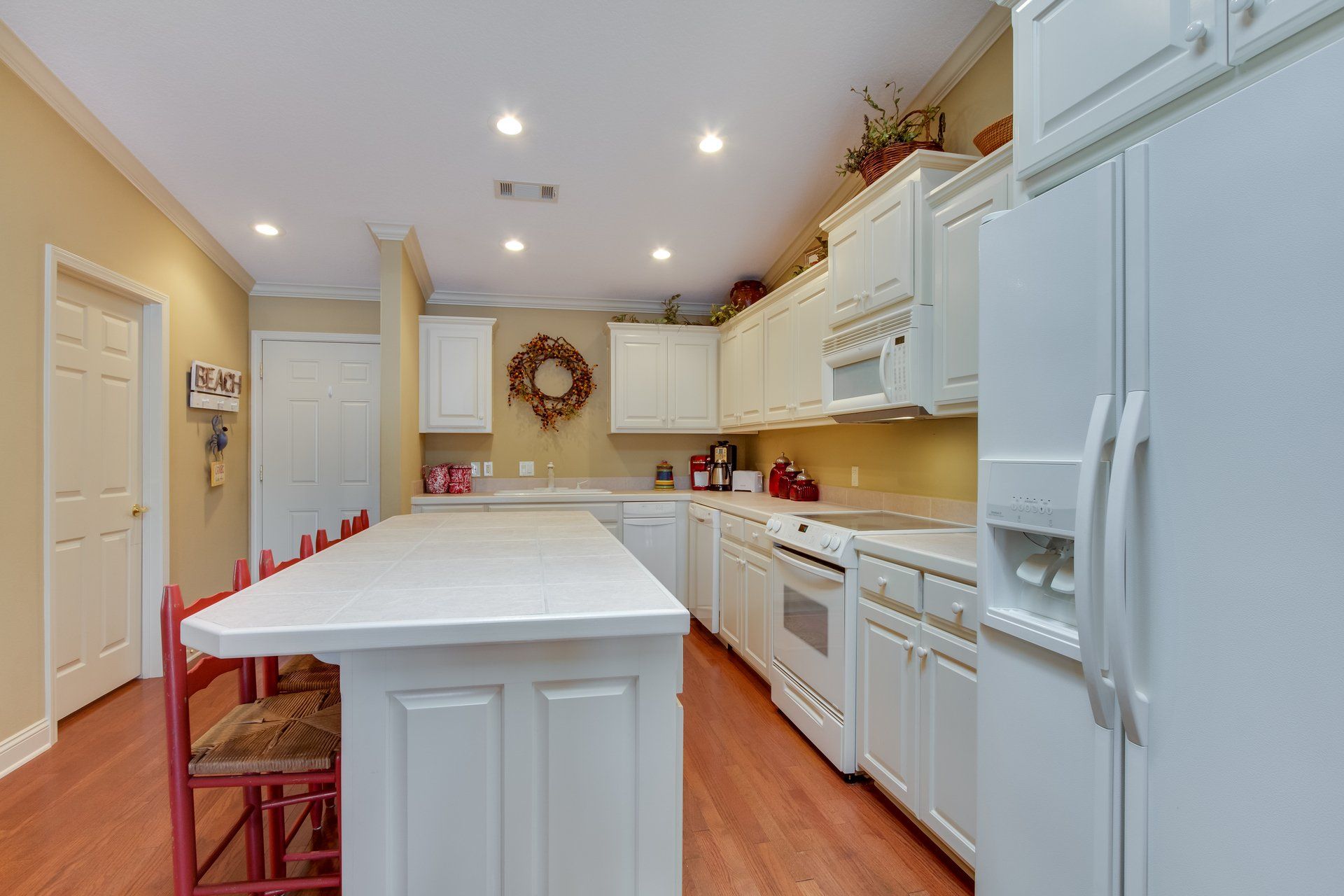 A kitchen with white cabinets , red chairs and a large island.