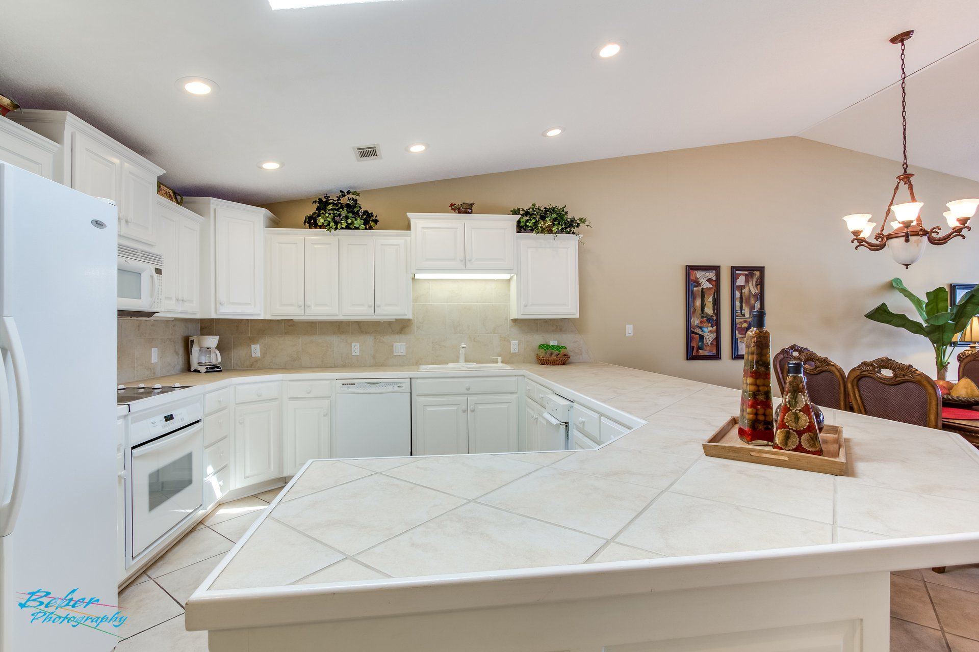 A kitchen with white cabinets , white appliances , and a large island.