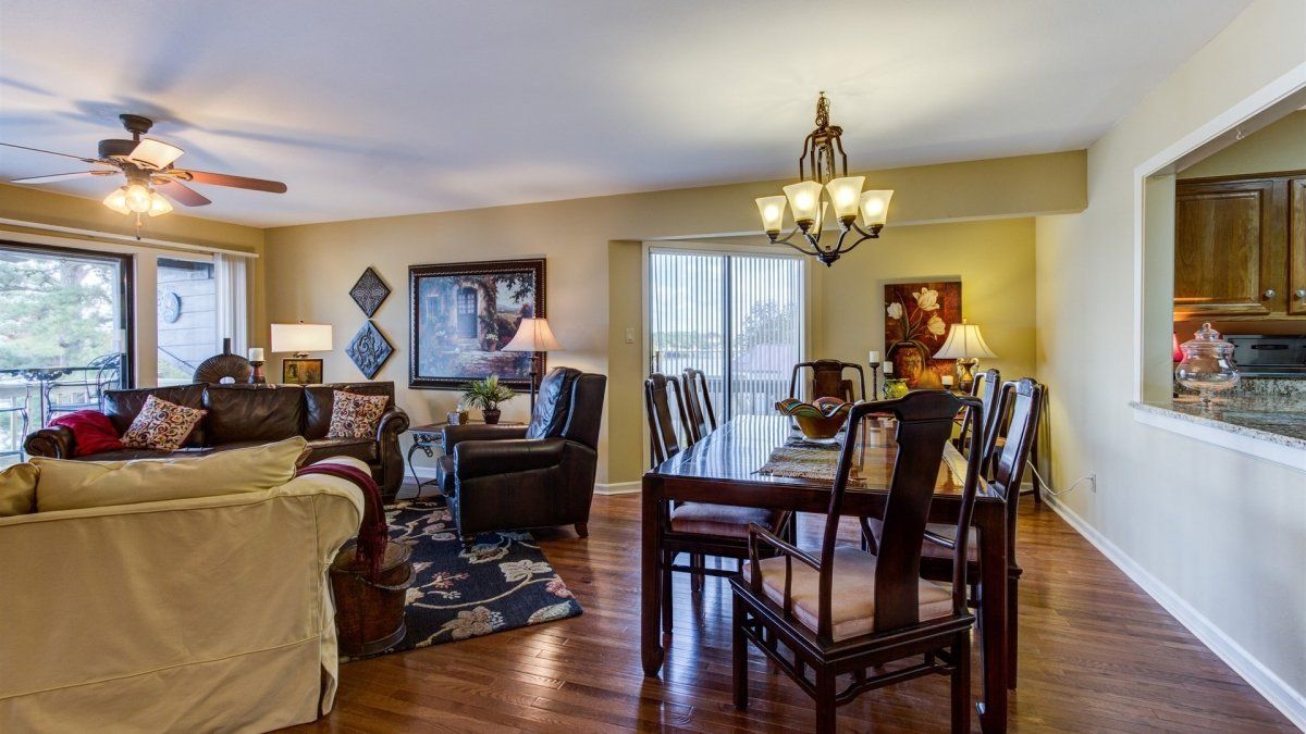 A living room with a dining table and chairs and a ceiling fan.