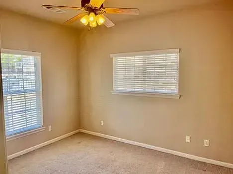 An empty bedroom with a ceiling fan and a window.