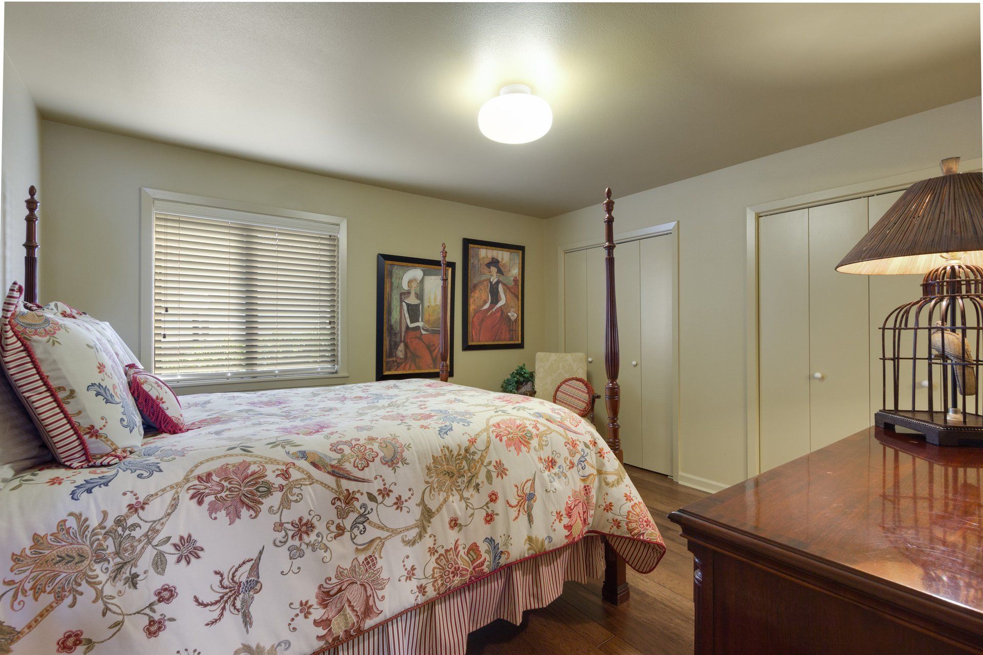 A bedroom with a large bed , dresser and lamp