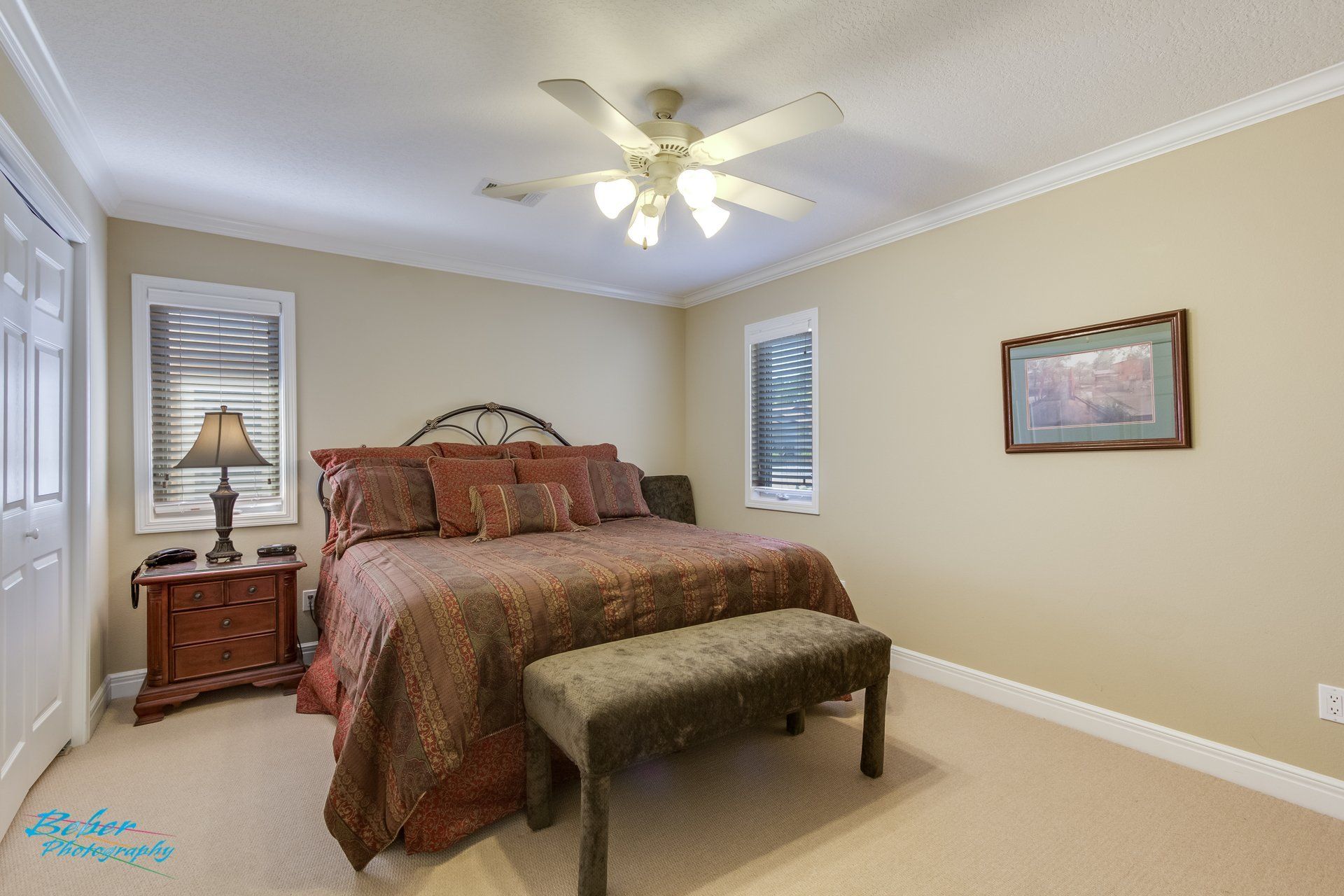 A bedroom with a king size bed and a ceiling fan.