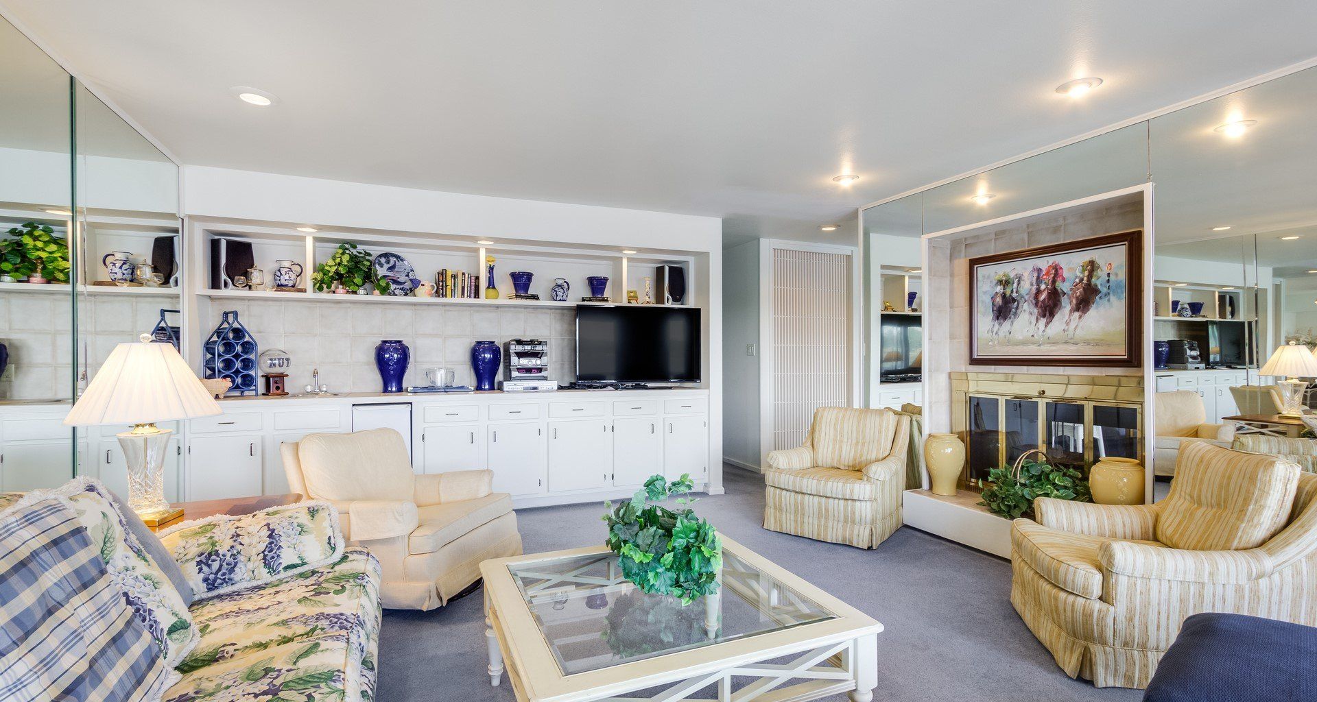 A living room with a couch , chairs , coffee table and television.