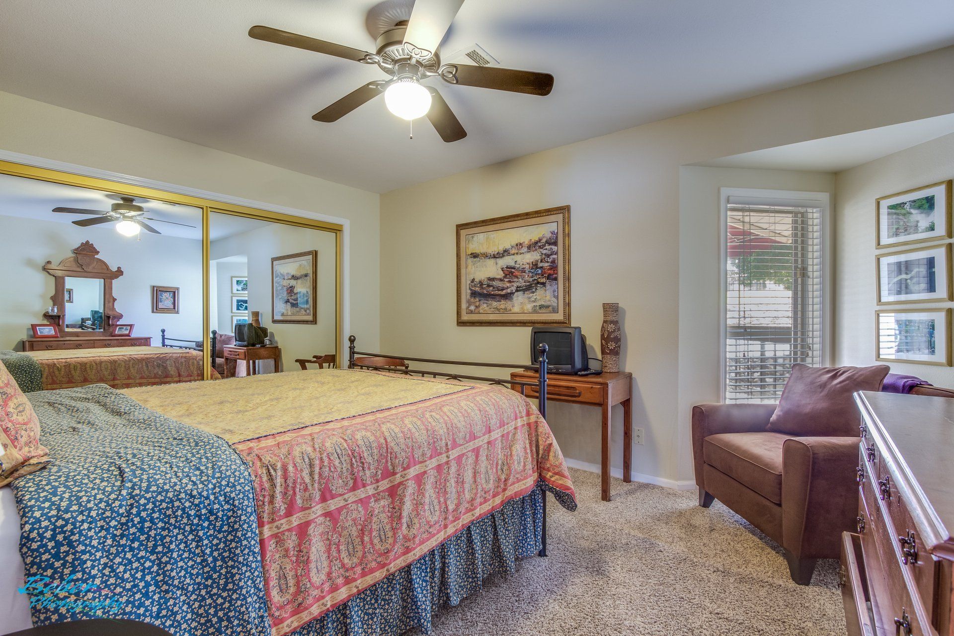 A bedroom with a bed , chair , desk and ceiling fan.