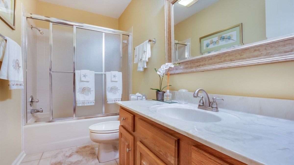 A bathroom with a sink , toilet , shower and mirror.