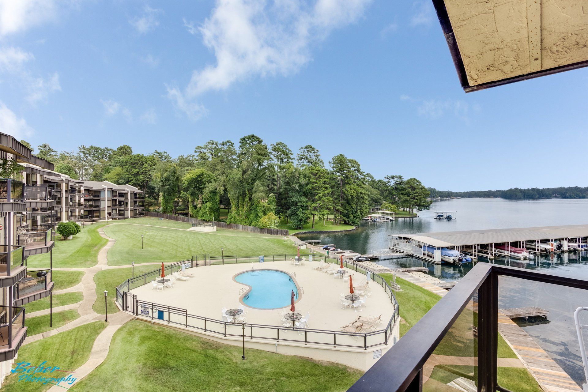 A view of a swimming pool from a balcony overlooking a lake.