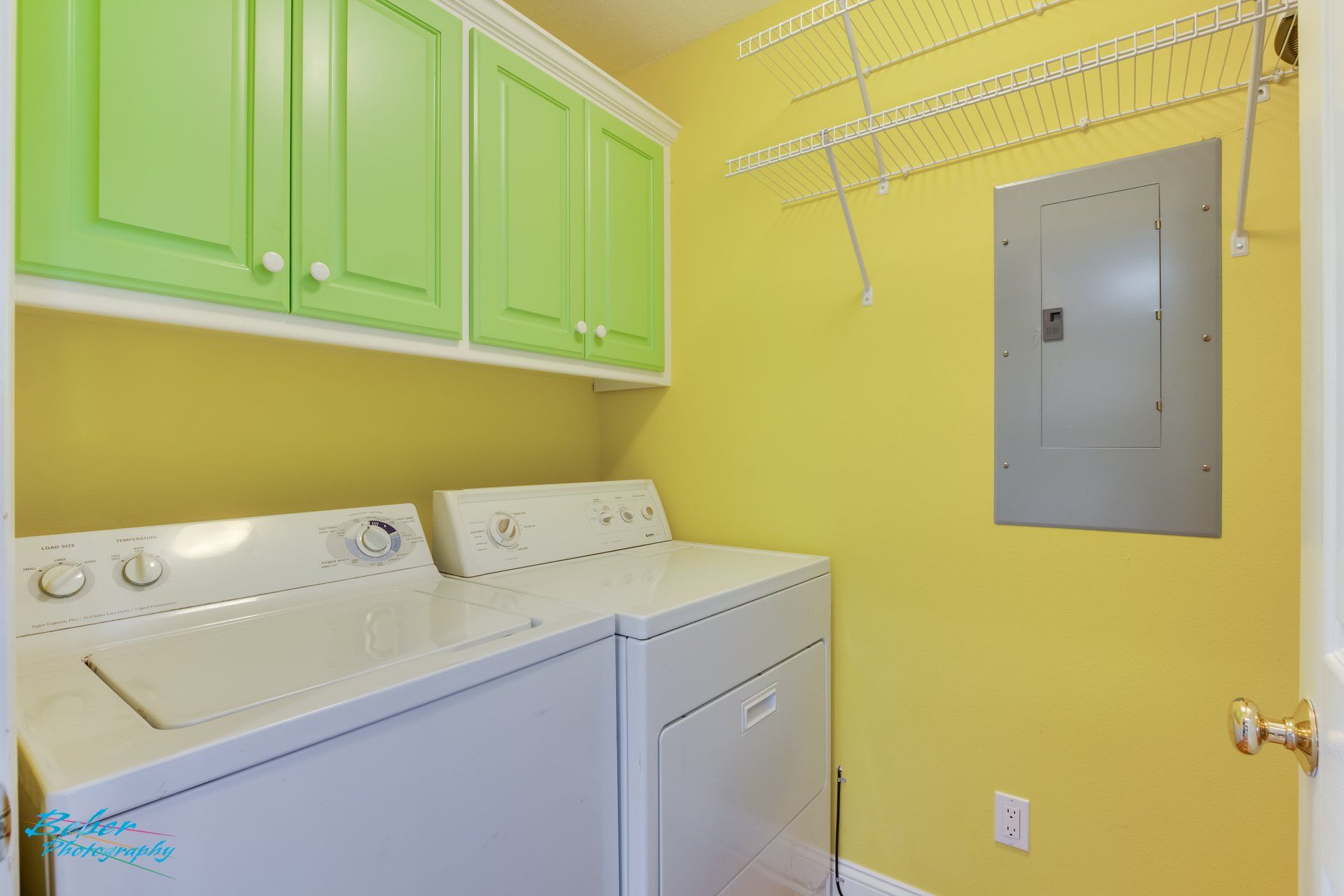 A laundry room with a washer and dryer and green cabinets.