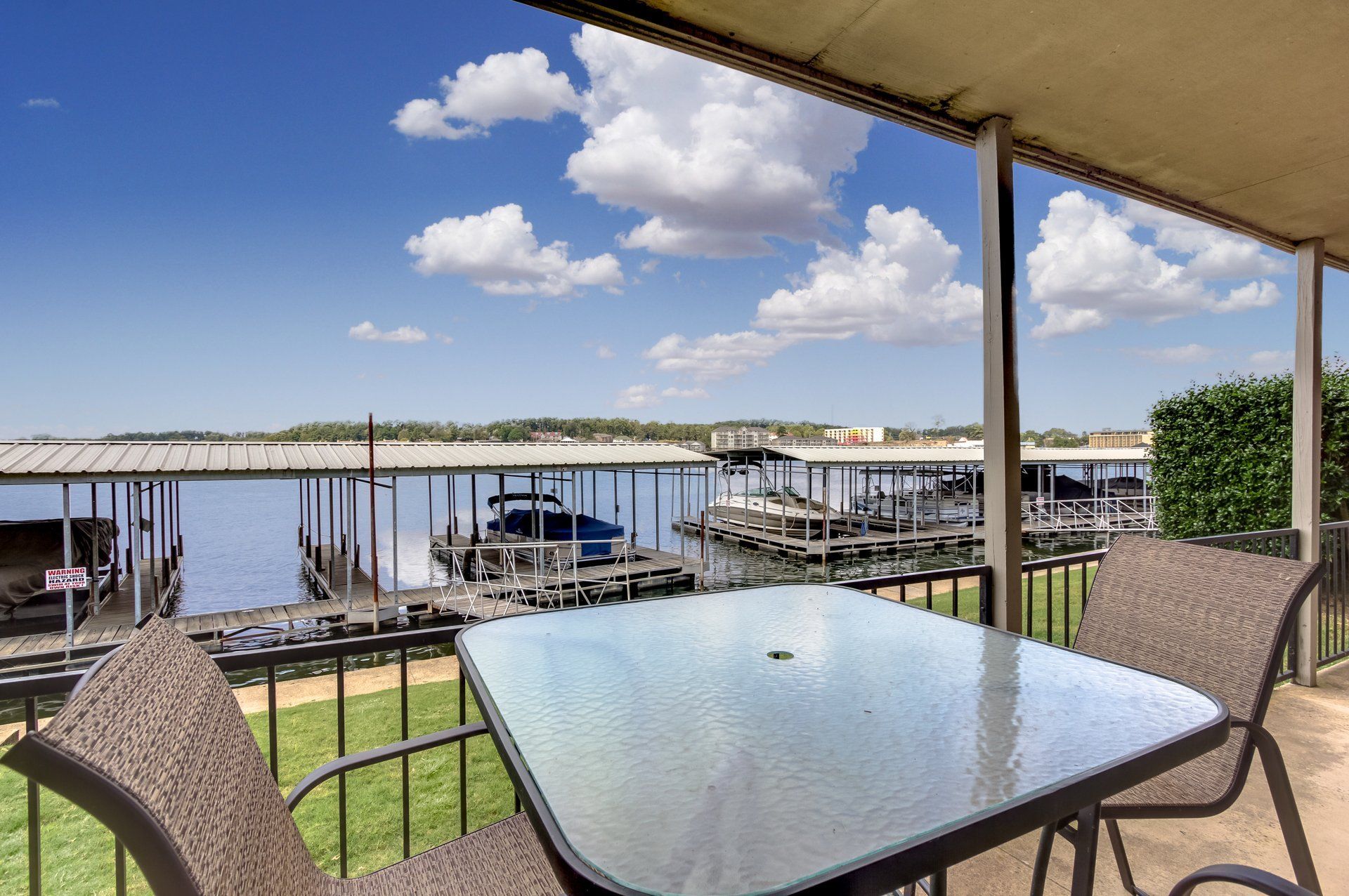 A table and chairs on a balcony overlooking a lake.