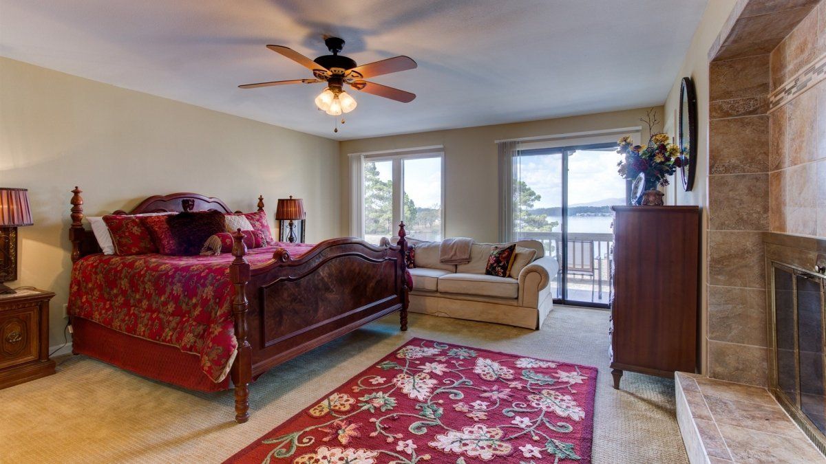 A bedroom with a bed , couch , rug and ceiling fan.