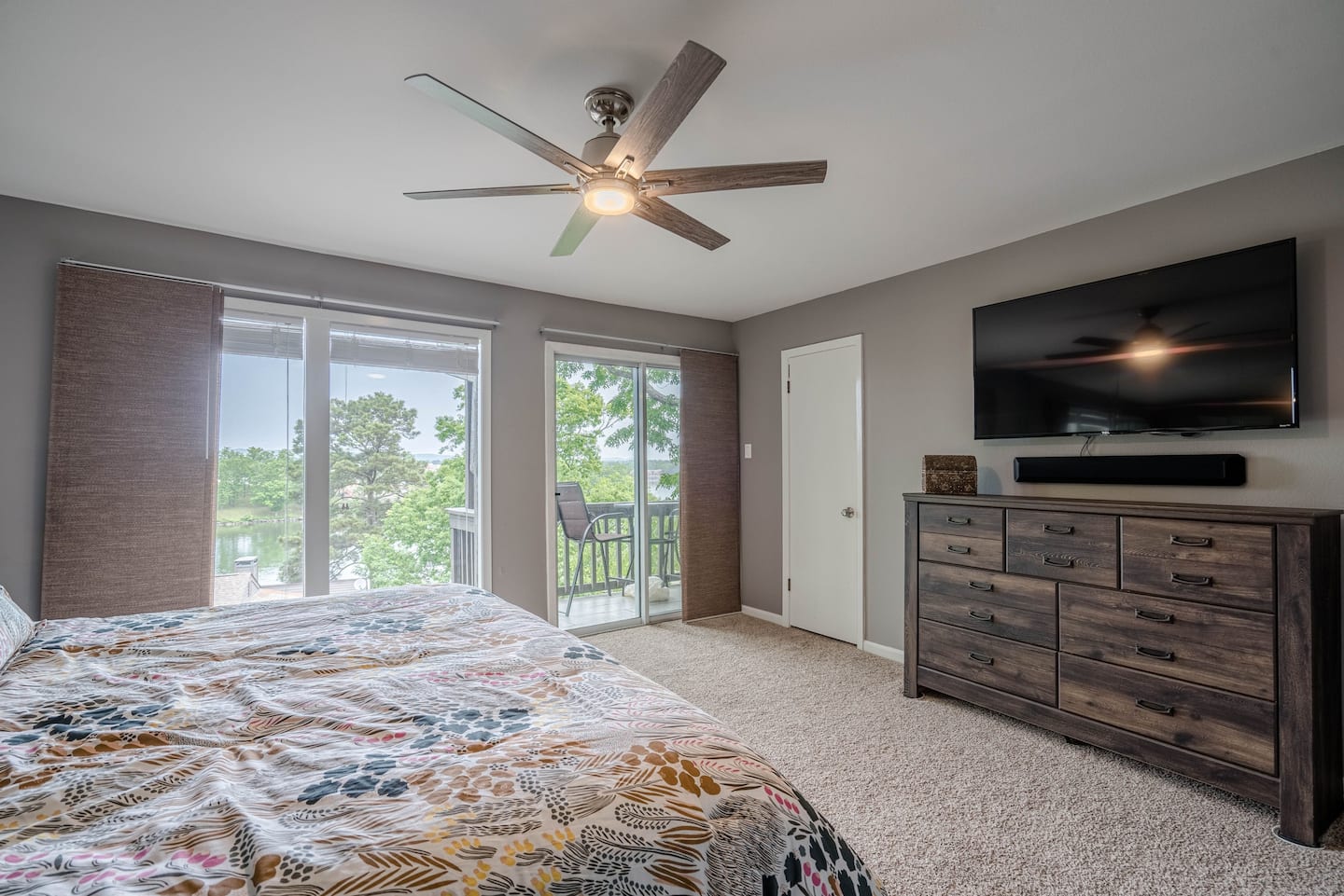 A bedroom with a bed , dresser , television and ceiling fan.